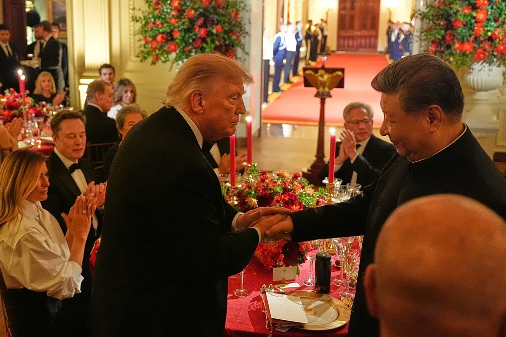 El presidente Donald Trump estrecha la mano del presidente chino Xi Jinping en la Sala Este de la Casa Blanca durante una Cena de Estado. De fondo, puede verse a Melania Trump, Elon Musk y Jensen Huang.